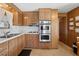 Functional kitchen with wooden cabinets, stainless steel oven appliances, and efficient layout for everyday cooking needs at 5306 Mary St, Zephyrhills, FL 33542