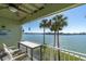 Cozy balcony with chairs and a table, offering a serene setting with beautiful water views and tropical palm trees at 553 Haven Point Dr, Treasure Island, FL 33706
