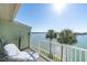 Relaxing waterfront balcony with lounge chair, table and stunning views of the water and palm trees at 553 Haven Point Dr, Treasure Island, FL 33706