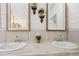 Close-up of dual sinks with marble countertop, framed mirrors, and charming wall decor at 5745 Pawnee St, Zephyrhills, FL 33542