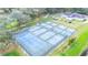 Overhead shot showing the community tennis courts with lush trees surrounding them and a clubhouse in the background at 5745 Pawnee St, Zephyrhills, FL 33542