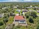 The aerial perspective highlights the home's terracotta roof amidst a setting abundant with lush trees and neighboring houses at 6968 De Brita Rd, North Port, FL 34291