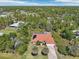 An elevated view of a single-Gathering home with lush surroundings, showcasing its terracotta roof and verdant lot at 6968 De Brita Rd, North Port, FL 34291