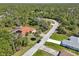 Aerial view of a single Gathering home with an orange tile roof and a screened in pool in a wooded neighborhood at 6968 De Brita Rd, North Port, FL 34291