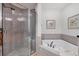 Bathroom featuring a tile shower with glass door, soaking tub, and attractive neutral color palette at 7710 Lake Vista Ct # 205, Lakewood Ranch, FL 34202