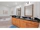 Bright bathroom with wood cabinets, dual sinks, granite counters, soaking tub, and stylish swan decoration at 7710 Lake Vista Ct # 205, Lakewood Ranch, FL 34202