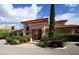 Inviting clubhouse exterior with a covered entrance, lush landscaping, and ample parking space at 7710 Lake Vista Ct # 205, Lakewood Ranch, FL 34202