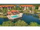 Incredible aerial view of the community pool and building on the water, surrounded by manicured trees and landscaping at 7710 Lake Vista Ct # 205, Lakewood Ranch, FL 34202