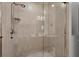 Walk-in tile shower with glass door featuring a handheld shower head and convenient shower shelf at 7710 Lake Vista Ct # 205, Lakewood Ranch, FL 34202