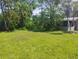 Expansive front yard featuring lush green grass and mature landscaping with a peek at the screened in porch at 11233 51St N Ave, St Petersburg, FL 33708