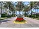 Scenic view of Grande entrance featuring palm trees, red flowers, and upscale condominiums at 1180 Gulf Blvd # 1201, Clearwater, FL 33767