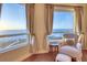 Bright living room with comfortable chair, footstool and ocean views from multiple windows at 1180 Gulf Blvd # 1201, Clearwater, FL 33767