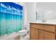 Well-lit bathroom featuring a stylish vanity, toilet, and bathtub with bright blue ocean-themed shower curtain at 14180 Samoa Hill Ct, Riverview, FL 33569
