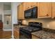 Well-equipped kitchen with granite countertops, wood cabinets, and black appliances at 14709 Coral Berry Dr, Tampa, FL 33626