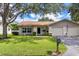 Single-story home featuring a manicured lawn and landscaping with a mailbox out front at 1497 Heather Ridge Blvd, Dunedin, FL 34698