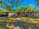 Charming single-story brick home featuring a covered carport, mature trees, and a well-manicured front yard at 1602 E Henry Ave, Tampa, FL 33610