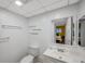 Bright bathroom featuring a toilet, sink, mirror, and shelving, with a view into the bedroom at 1801 Bedford Ter # 221, Sun City Center, FL 33573