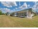 Rear view of a single story home with an enclosed porch and large grassy yard at 1801 Bedford Ter # 221, Sun City Center, FL 33573