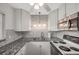 Kitchen boasts granite countertops, tile backsplash, white cabinets, stove, and stainless steel microwave at 1801 Bedford Ter # 221, Sun City Center, FL 33573