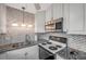 Kitchen boasts white cabinets, tile backsplash, granite countertops, and stainless steel microwave and stove at 1801 Bedford Ter # 221, Sun City Center, FL 33573