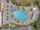 Overhead shot of a beautiful pool with a stone deck, many lounge chairs, landscaping, and tables with umbrellas at 1801 Bedford Ter # 221, Sun City Center, FL 33573
