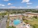 Aerial view of a community pool with lounge chairs, umbrellas, landscaping, and a clubhouse with a parking lot at 1801 Bedford Ter # 221, Sun City Center, FL 33573