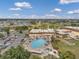 Aerial view of a community pool surrounded by lounge chairs, umbrellas, landscaping, and a clubhouse at 1801 Bedford Ter # 221, Sun City Center, FL 33573