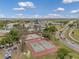 Aerial view of well-maintained tennis courts surrounded by lush greenery and community roads under a bright, sunny sky at 1801 Bedford Ter # 221, Sun City Center, FL 33573