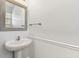 Bright half bathroom featuring a pedestal sink, decorative mirror, and wainscoting at 1869 Hovenweep Rd, Wesley Chapel, FL 33543