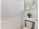 Charming half bathroom with wainscoting, featuring a toilet with decorative shelf and a bouquet of sunflowers at 1869 Hovenweep Rd, Wesley Chapel, FL 33543