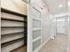 Hallway with tile floors features a storage area closed off by a glass sliding barn door at 1869 Hovenweep Rd, Wesley Chapel, FL 33543