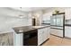 Open-concept kitchen with granite countertops, island with sink, white cabinets and stainless-steel refrigerator at 1869 Hovenweep Rd, Wesley Chapel, FL 33543