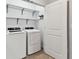 This laundry room features a washer, dryer, and metal shelving at 1869 Hovenweep Rd, Wesley Chapel, FL 33543