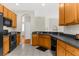 Well-lit kitchen with tile floors, an undermount sink, and wood cabinets with black appliances at 200 Fairmont Dr, Spring Hill, FL 34609