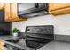 A kitchen showcases an electric range stove top with an overhead microwave and wood cabinets at 200 Fairmont Dr, Spring Hill, FL 34609