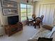 A sunroom with large windows is furnished with a TV, rattan chairs, and a sofa at 2428 Columbia Dr # 72, Clearwater, FL 33763