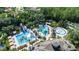 Aerial view of community pools, waterslides, clubhouse, lush landscaping, and parking at 27524 Pine Point Dr, Wesley Chapel, FL 33544