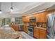Bright kitchen with granite countertops, wood cabinets, stainless steel appliances, and a view of the pool at 3267 Westcott Ct, Palm Harbor, FL 34684