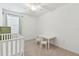 Light and airy bedroom features a window, crib, small table, and soft neutral carpeting at 4326 Banjo Lake Rd, Land O Lakes, FL 34639