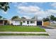 Well-maintained single-story home featuring a blacktop driveway, shuttered windows and a green lawn at 4601 71St N Ave, Pinellas Park, FL 33781