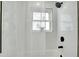 Close-up view of a tiled shower with a window, featuring black shower head, faucet, and shower caddy at 4601 71St N Ave, Pinellas Park, FL 33781