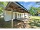 Backyard view with a white brick house and a covered patio with a wooden deck and steel roof at 513 E Langford Dr, Plant City, FL 33563