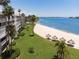 Beautiful beach view with white sand, shady tiki huts, and well-maintained green spaces near the condos at 5701 Bahia Del Mar Cir # 408, St Petersburg, FL 33715