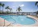 Community pool with clear blue water, lounge chairs, and tropical landscaping under a clear sky at 5701 Bahia Del Mar Cir # 408, St Petersburg, FL 33715