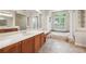 Bathroom featuring a soaking tub with a large window, double sink vanity, and decorative tile at 6130 Kestrelridge Dr, Lithia, FL 33547