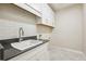 Well-lit laundry room features a sink, countertop, and upper cabinets for storage at 6130 Kestrelridge Dr, Lithia, FL 33547