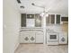 Kitchen featuring white appliances and cabinets, tile backsplash, and tiled floors at 6228 Monroe St, New Port Richey, FL 34653