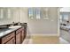 Bright bathroom with tile floor, wood cabinet, granite counter, and sink; natural light from three windows at 6324 Brevada Ln, Apollo Beach, FL 33572