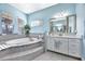 Main bathroom featuring a soaking tub, large vanity, and many windows for natural light at 6324 Brevada Ln, Apollo Beach, FL 33572