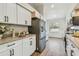 Well-lit kitchen with stainless steel refrigerator, granite counters, white cabinets, and wood-look vinyl floors at 6680 67Th N Way, Pinellas Park, FL 33781
